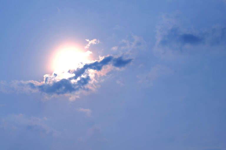 Sonne scheint durch Wolken am blauen Himmel