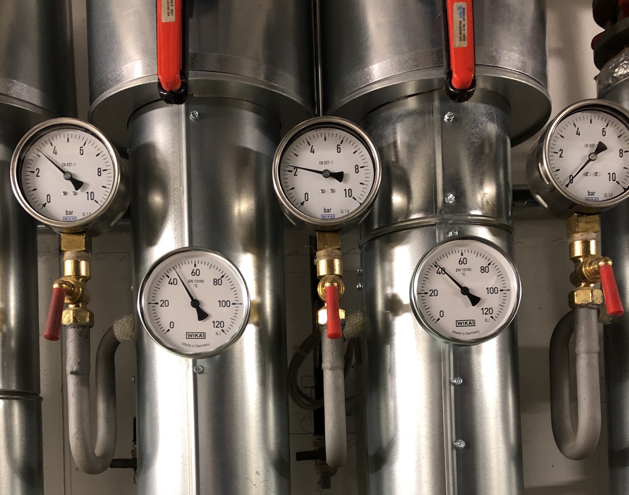 Druck- und Temperaturanzeigen (WIKA-Manometer) an gedämmten Rohrleitungen einer Heizungsanlage